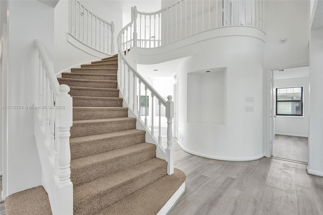 stairway featuring a high ceiling and hardwood / wood-style floors