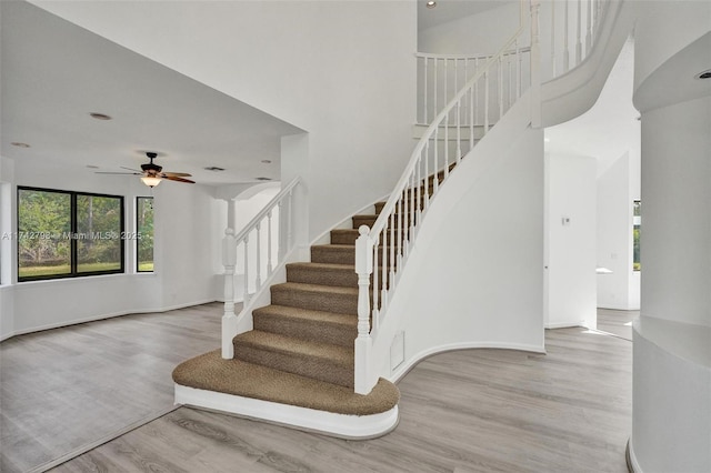 stairway featuring hardwood / wood-style flooring, ceiling fan, and a towering ceiling