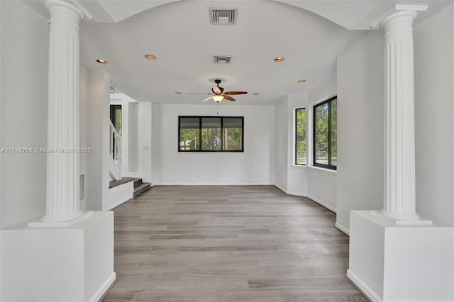 unfurnished living room with ornate columns, ceiling fan, and light wood-type flooring