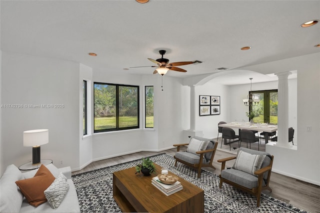 living room with ceiling fan, a healthy amount of sunlight, hardwood / wood-style floors, and ornate columns