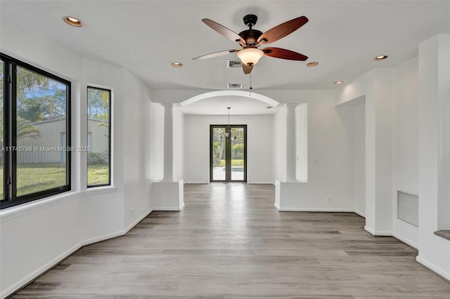 unfurnished room featuring ornate columns, ceiling fan, and light wood-type flooring