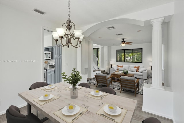 dining area with ornate columns, ceiling fan with notable chandelier, and light wood-type flooring