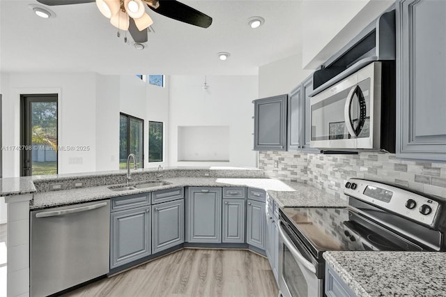 kitchen with stainless steel appliances, sink, gray cabinetry, and kitchen peninsula