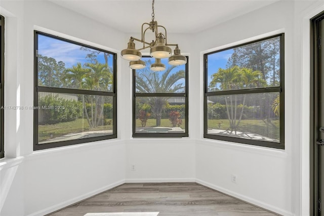 unfurnished dining area with wood-type flooring and an inviting chandelier