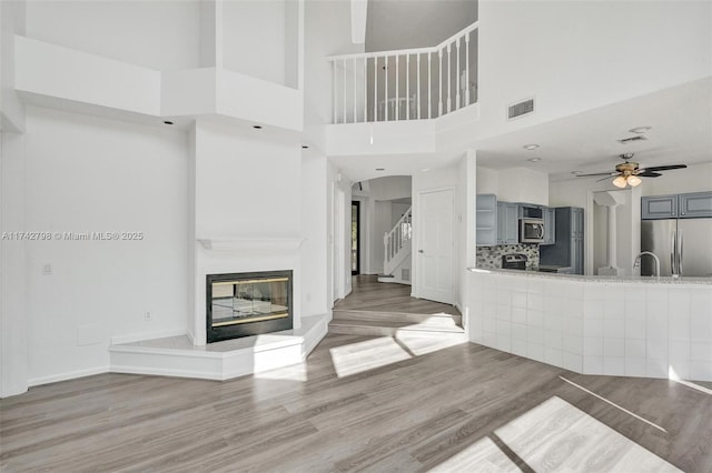 unfurnished living room with sink, hardwood / wood-style flooring, and ceiling fan