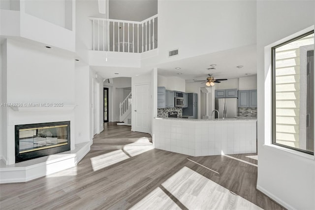 unfurnished living room featuring wood-type flooring and ceiling fan