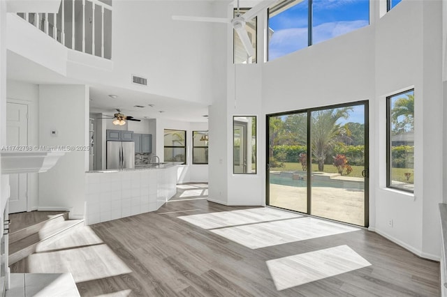 unfurnished living room with sink, ceiling fan, and light wood-type flooring