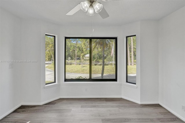 unfurnished room with ceiling fan, a textured ceiling, light hardwood / wood-style flooring, and a healthy amount of sunlight