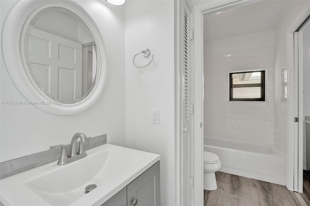 full bathroom featuring hardwood / wood-style flooring, vanity, toilet, and tiled shower / bath combo