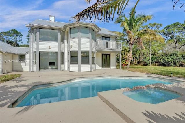 rear view of house featuring a balcony, a patio area, and a pool with hot tub