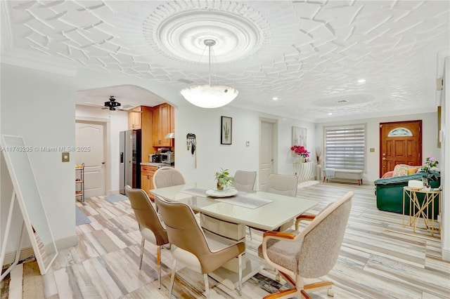 dining room featuring baseboards, arched walkways, and ceiling fan