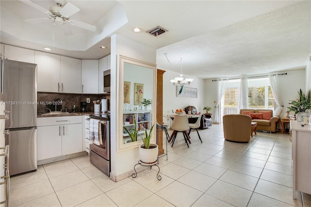 kitchen featuring appliances with stainless steel finishes, white cabinets, decorative backsplash, hanging light fixtures, and light tile patterned floors