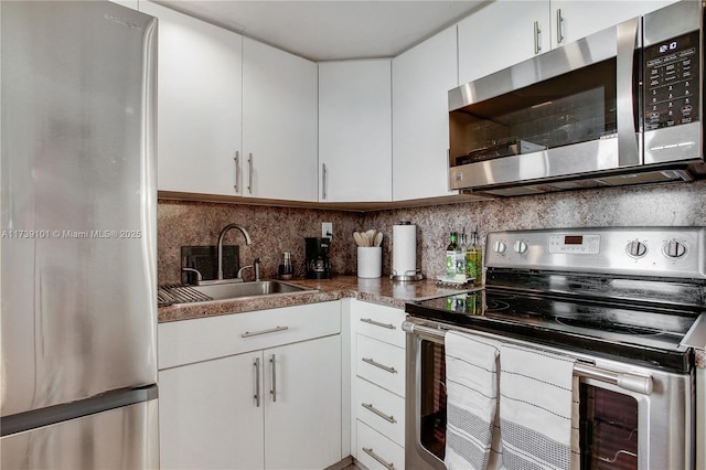 kitchen with white cabinetry, stainless steel appliances, sink, and backsplash