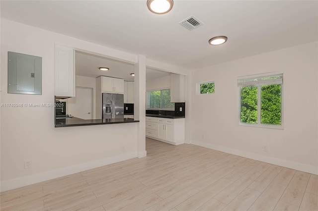 unfurnished living room featuring electric panel and light wood-type flooring