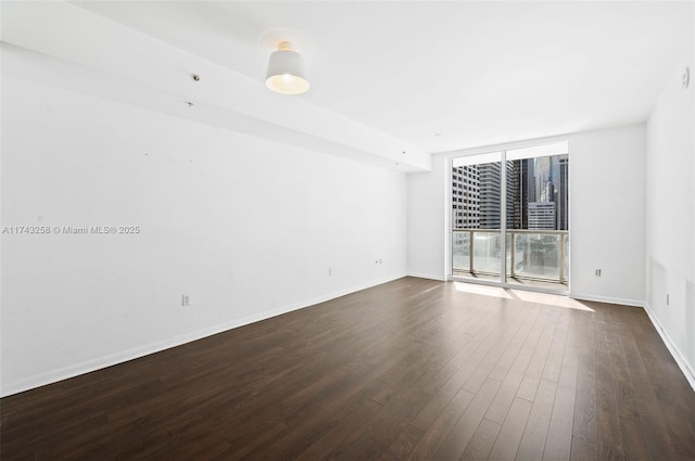 empty room with a wall of windows and dark hardwood / wood-style flooring