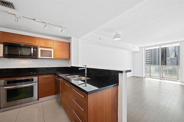 kitchen featuring appliances with stainless steel finishes, sink, floor to ceiling windows, and kitchen peninsula