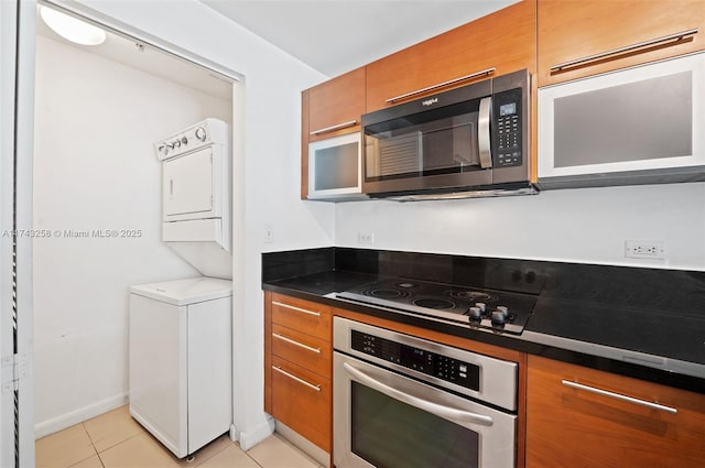 kitchen featuring appliances with stainless steel finishes, light tile patterned floors, and stacked washer and clothes dryer