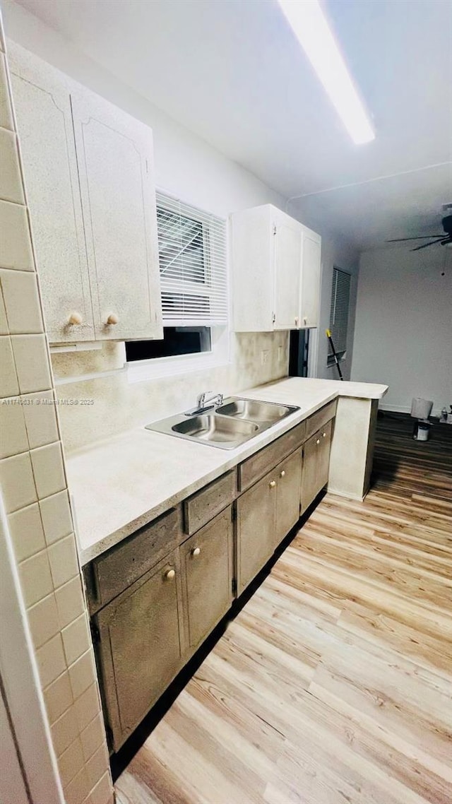 kitchen with white cabinetry, ceiling fan, sink, and light hardwood / wood-style flooring