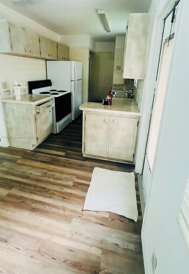 kitchen with white appliances, wood-type flooring, and sink