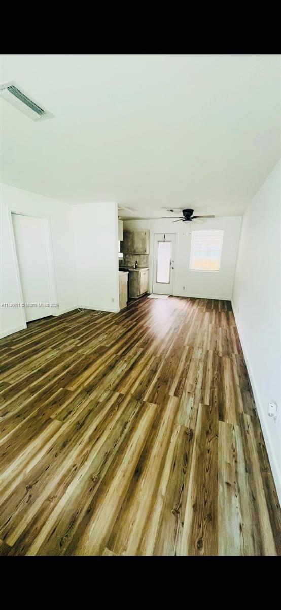 unfurnished living room featuring dark hardwood / wood-style floors and ceiling fan