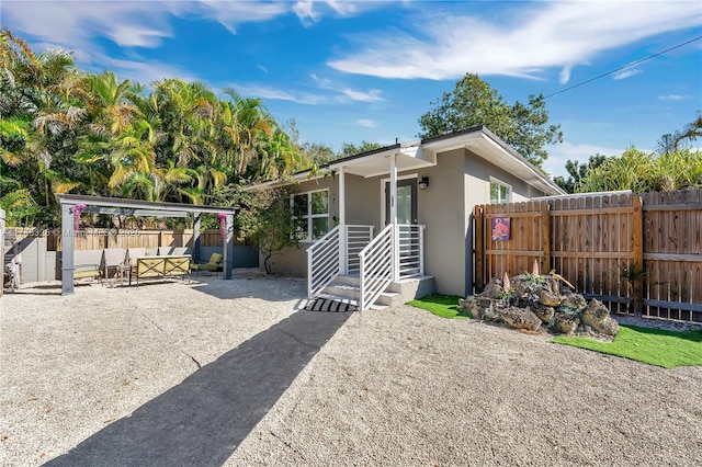 view of front of property featuring fence, a patio, and stucco siding