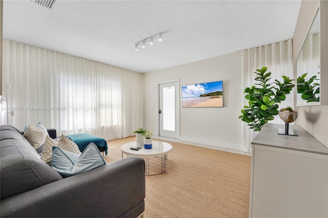 living area featuring light tile patterned floors, light carpet, visible vents, baseboards, and rail lighting