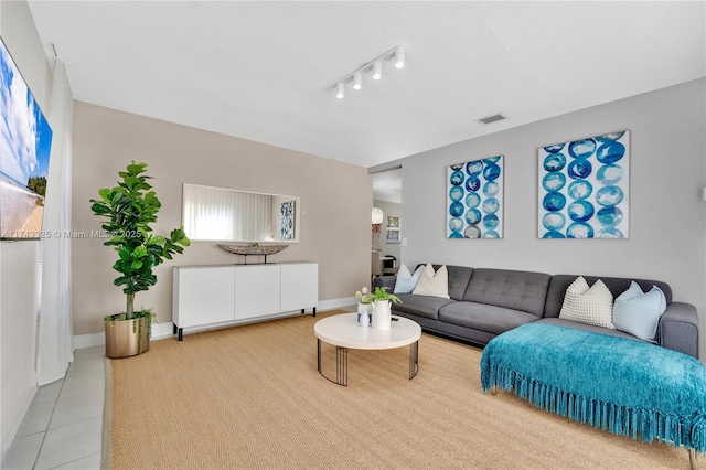 living area with light tile patterned floors, baseboards, visible vents, and rail lighting