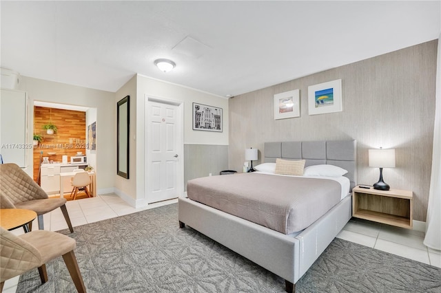 bedroom featuring an accent wall, baseboards, and tile patterned floors