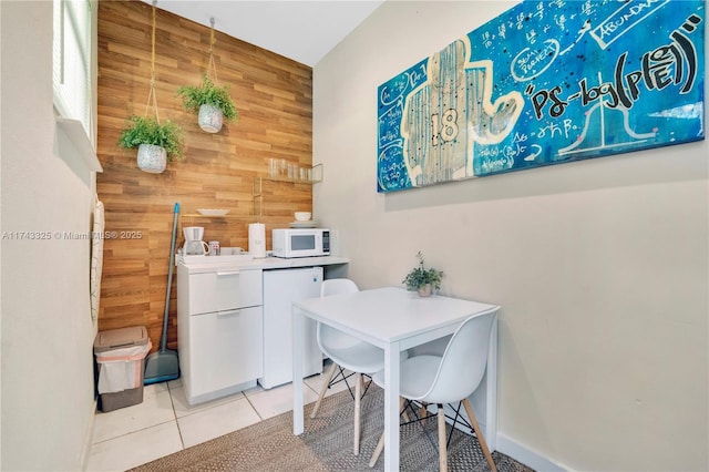 dining room featuring wooden walls and tile patterned floors