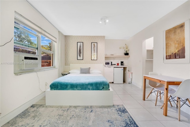 bedroom with an accent wall, refrigerator, light tile patterned flooring, and baseboards