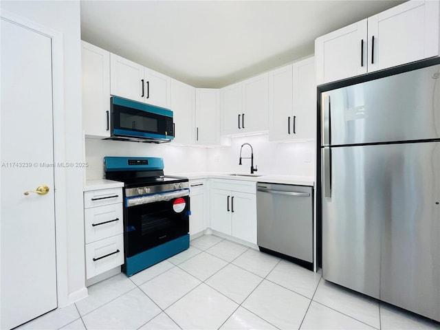 kitchen with light tile patterned flooring, appliances with stainless steel finishes, sink, and white cabinets