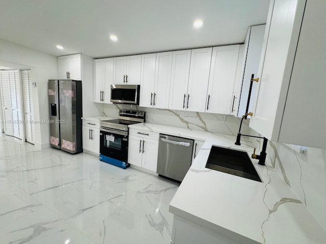 kitchen featuring sink, appliances with stainless steel finishes, light stone countertops, white cabinets, and decorative backsplash