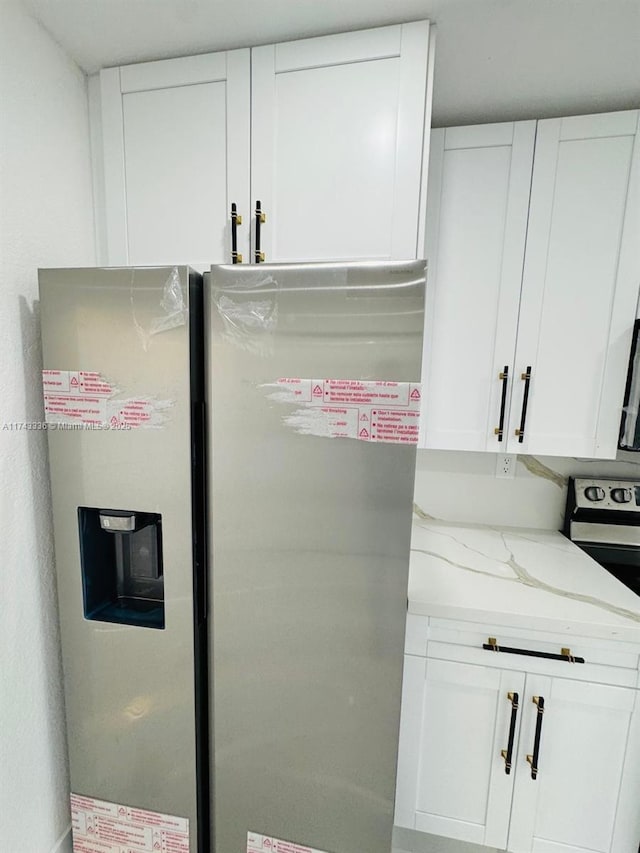 room details featuring white cabinetry, light stone counters, and stainless steel appliances