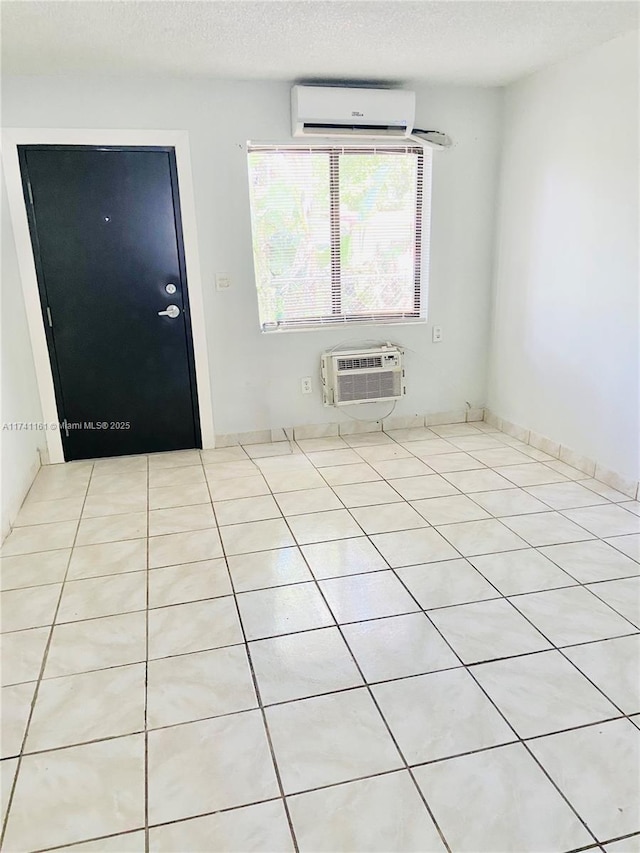 empty room with a wall unit AC and a textured ceiling