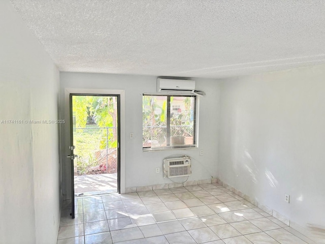 spare room featuring a wall mounted AC, a textured ceiling, and light tile patterned floors