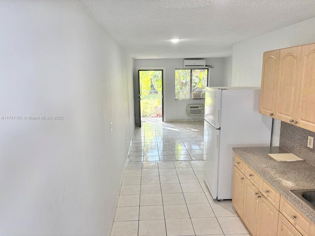 kitchen featuring light brown cabinetry, light tile patterned flooring, an AC wall unit, and white refrigerator