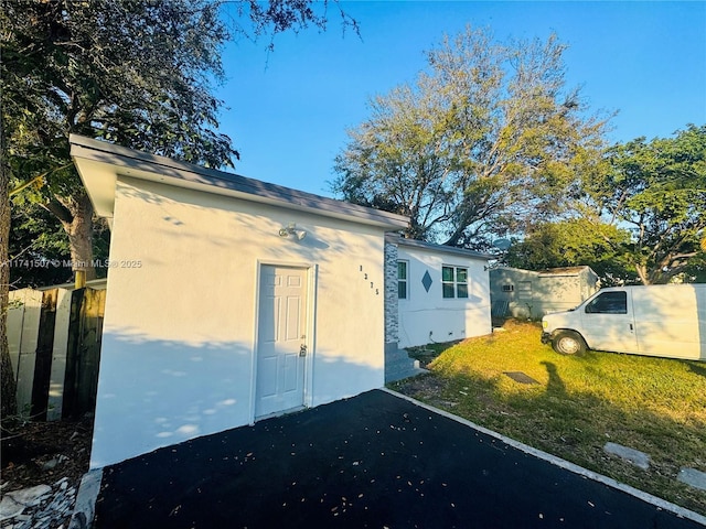 view of home's exterior with an outbuilding, fence, and stucco siding