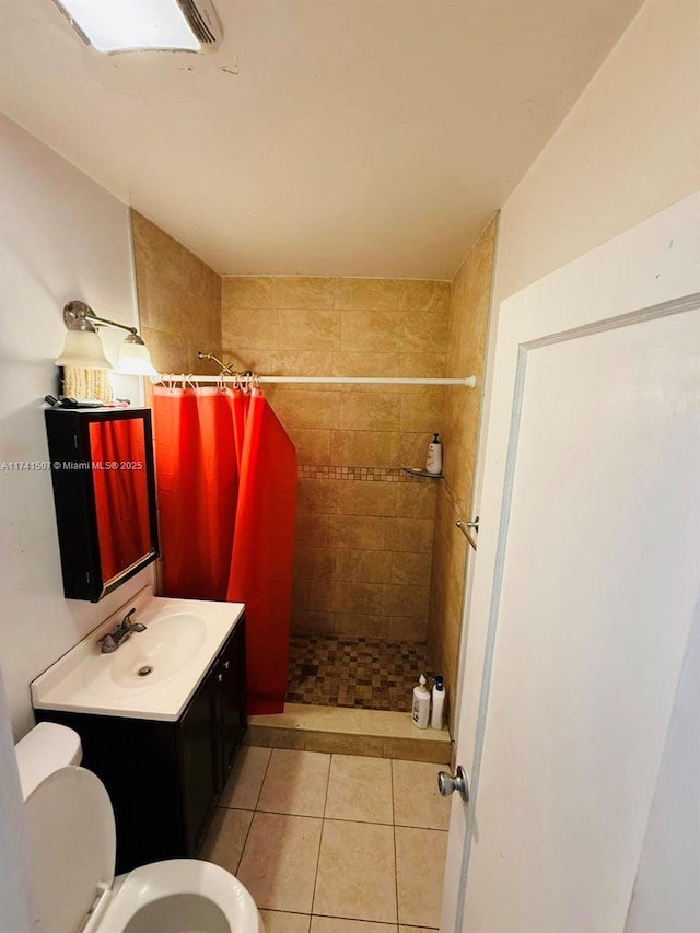 full bath with toilet, vanity, tiled shower, and tile patterned floors