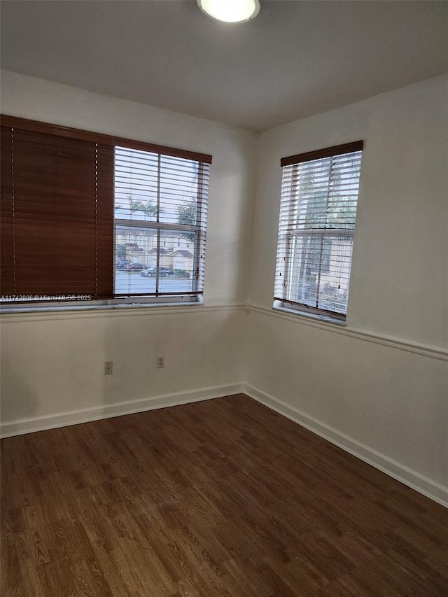 empty room with a wealth of natural light and dark wood-type flooring