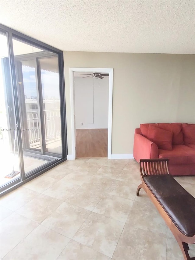 living room featuring ceiling fan, a wall of windows, and a textured ceiling