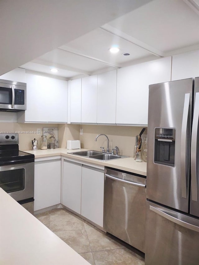 kitchen with white cabinetry, appliances with stainless steel finishes, sink, and light tile patterned flooring