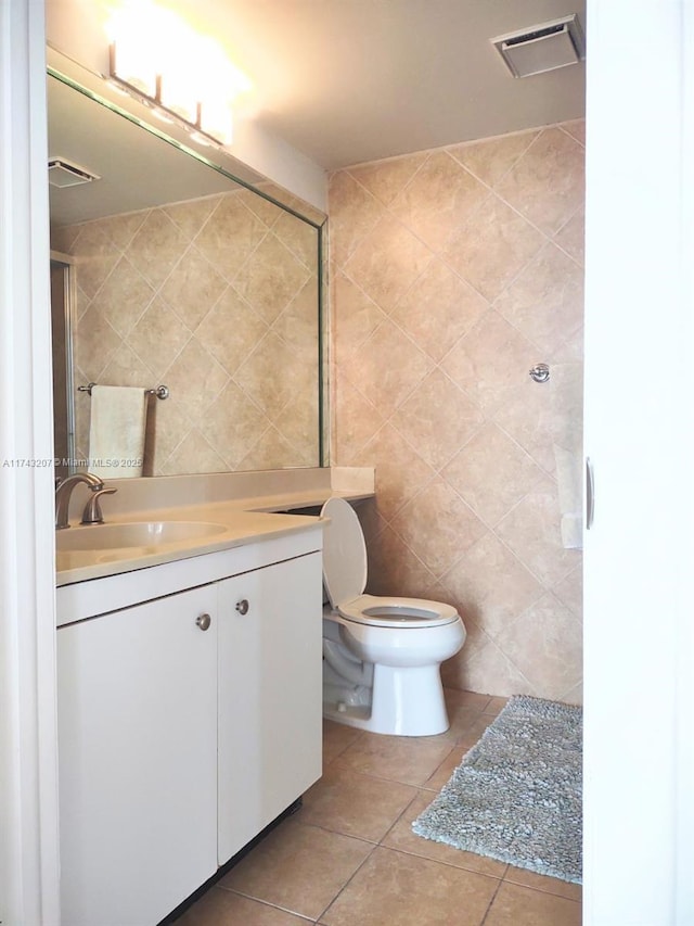 bathroom featuring tile patterned flooring, vanity, tile walls, and toilet