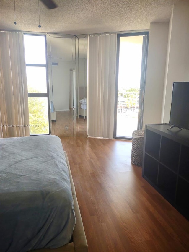 bedroom featuring hardwood / wood-style flooring, access to outside, a textured ceiling, and multiple windows