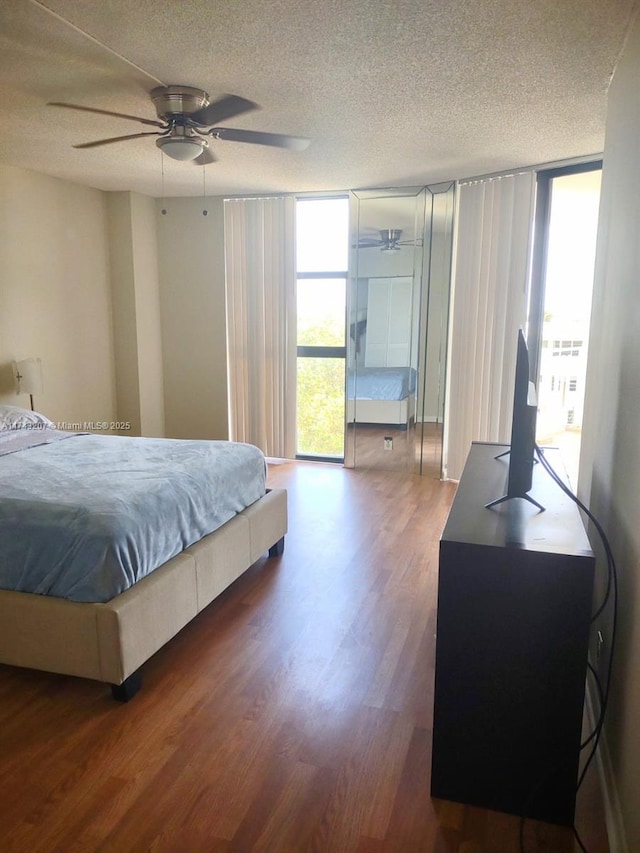 bedroom featuring multiple windows, a wall of windows, dark hardwood / wood-style floors, and a textured ceiling