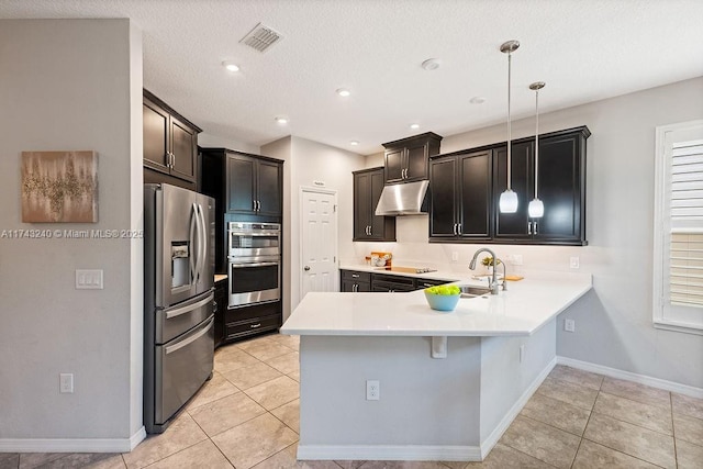 kitchen with pendant lighting, sink, appliances with stainless steel finishes, light tile patterned flooring, and kitchen peninsula