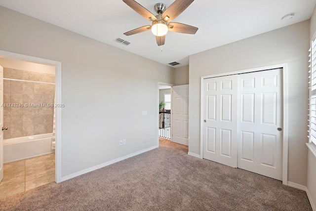 unfurnished bedroom featuring ceiling fan, light colored carpet, connected bathroom, and a closet