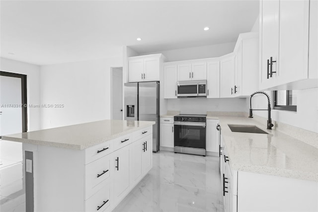 kitchen featuring white cabinetry, sink, a center island, stainless steel appliances, and light stone countertops