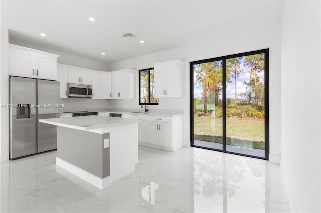 kitchen featuring stainless steel appliances, a center island, sink, and white cabinets