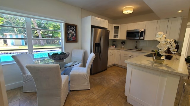 kitchen featuring white cabinets, glass insert cabinets, light stone counters, stainless steel appliances, and backsplash