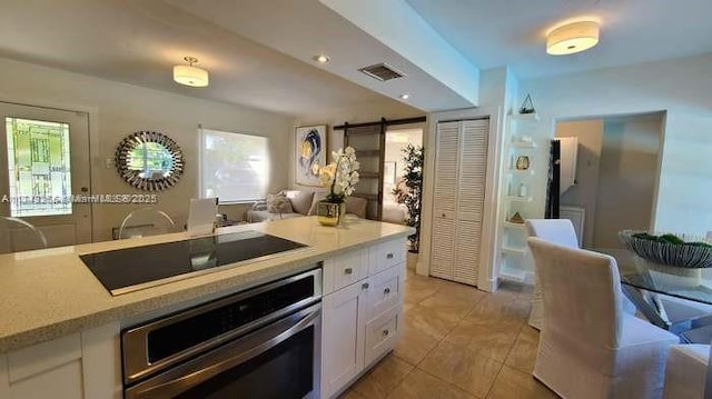 kitchen featuring white cabinetry, stainless steel oven, black electric cooktop, and a barn door